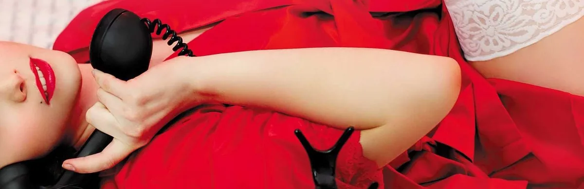 Femme en satin rouge, combiné noir, sourire aux lèvres rouges — numéro rose coquin